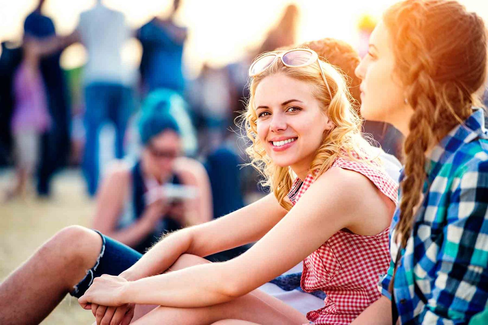 Two girls sitting in the grass and enjoying a music festival